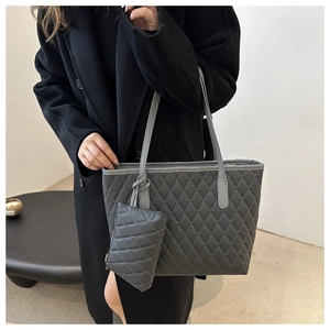 Gros plan d'un sac cabas gris matelassé avec une pochette assortie et des anses en cuir