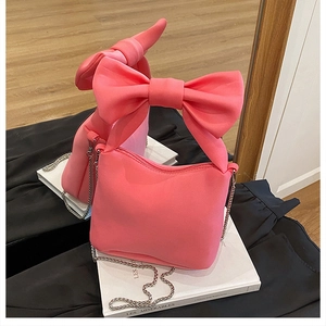 Close-up of bright pink shoulder bag with large bow detail and silver chain strap