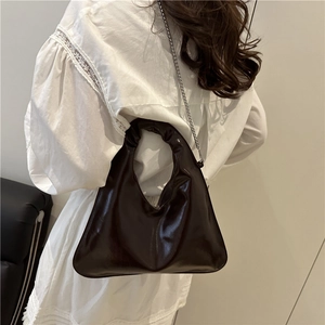 Fashionable dark brown ruched handle tote bag with silver chain strap shown on model