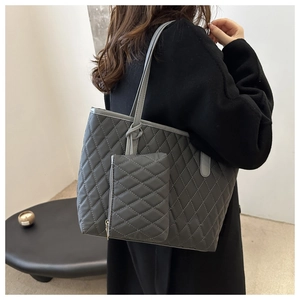 Grand sac cabas matelassé gris avec pochette assortie porté par un mannequin