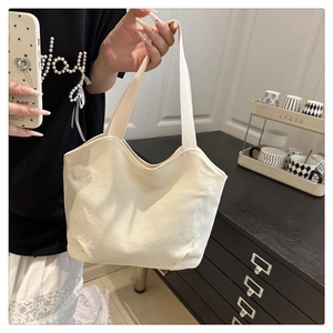 Detailed side view of the off-white canvas tote bag with reinforced woven handles