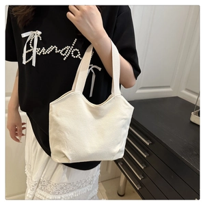 Detail of minimalist cream canvas tote bag with wavy edges and woven handles