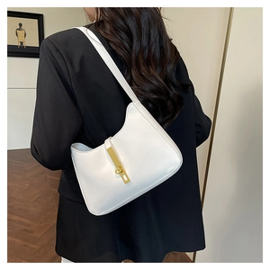 Détail d'un sac porté épaule demi-lune blanc avec boucle dorée sur un blazer noir