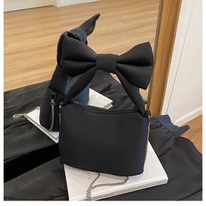 Detail of chic black bow-knot crossbody bag with matte texture and fine metal chain