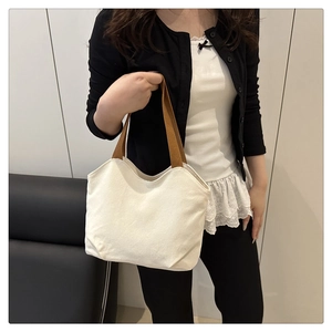 Minimalist canvas tote bag with brown woven handles shown on model in a casual setting