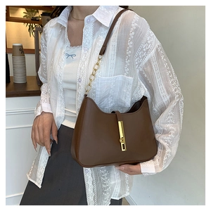 Détail d'un sac à bandoulière en cuir marron avec fermoir doré et bandoulière chaîne