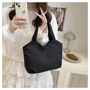 Close-up detail of the durable black canvas tote bag with reinforced handles in a cozy setting