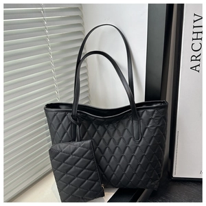 Détail du sac cabas matelassé noir avec pochette assortie sur fond minimaliste