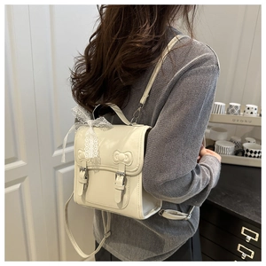 Close-up of a cream lace bow backpack with elegant embossed details on a model