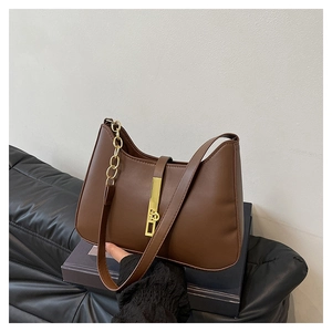 Détail d'un sac à bandoulière en similicuir marron avec boucle dorée sur un canapé