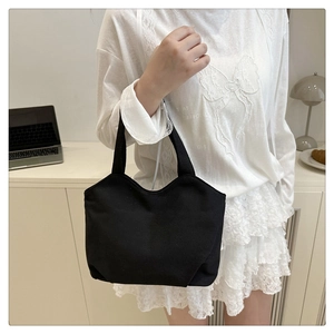 Close-up of black canvas tote bag with a unique wavy edge design and dual handles