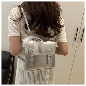 Macro view of silver metallic backpack with twin bow details and lace charm accent