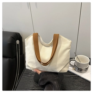 Detail of minimalist cream canvas tote bag with brown woven handle for casual daily use