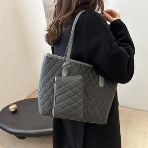 Sac fourre-tout matelassé gris foncé avec pochette assortie, porté à l'épaule par une femme