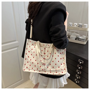 Close-up of cream corduroy tote bag with red heart patterns and detachable strap