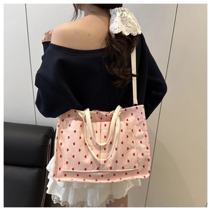 Pink corduroy tote bag with red heart patterns and dual shoulder straps shown on model
