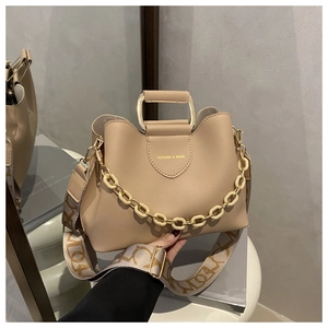 Close-up of apricot leather handbag with gold metal handle and jacquard strap