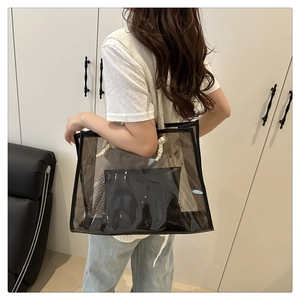 Detail view of transparent PVC tote bag with white cotton rope handles and black inner pouch