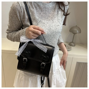 Close-up of black PU leather satchel featuring lace ribbons and bow relief decorations