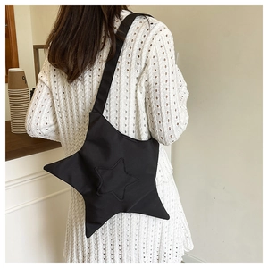 Gros plan d'un sac bandoulière noir en forme d'étoile sur une robe en maille blanche
