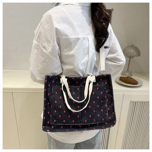 Detail of dark blue corduroy tote bag with red hearts and dual handles for crossbody use