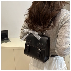 Detailed view of black PU leather backpack featuring chic bows and white lace ribbons