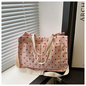 Detailed texture of pink corduroy tote bag with red hearts and large front pockets