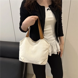 Minimalist white canvas tote bag with brown handles and curved top design for daily use