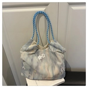 Detail of canvas tote bag featuring watercolor floral print and woven rope handle strap