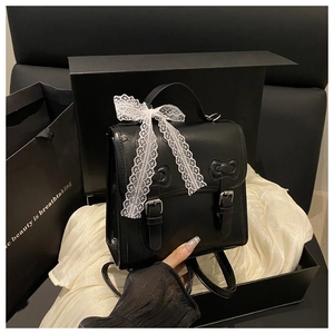 Detailed close-up of a black PU leather backpack with a white lace bow on a gift box