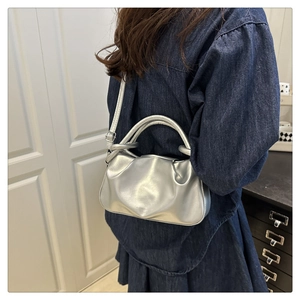 Detail of silver metallic dumpling bag with ruched design and thick top handles
