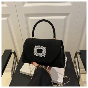 Dettaglio borsa in camoscio nero con fibbia di strass e catena dorata