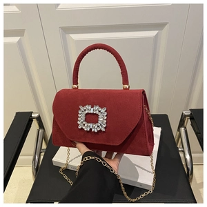 Dettaglio di borsa in camoscio rosso con fibbia quadrata di cristallo e catena dorata