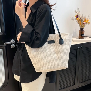 Minimalist straw tote bag for summer with black straps and fashion leather label detail