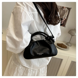 Detailed view of black pleated cloud handbag with white logo in a lifestyle home setting