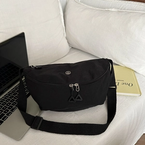 Détail du sac ceinture en nylon noir avec logo M en métal et large bandoulière tissée
