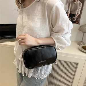 Sac à bandoulière minimaliste en cuir noir brillant avec fine chaîne argentée élégante