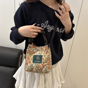 Floral brocade bucket bag with adjustable strap worn by model in casual street style