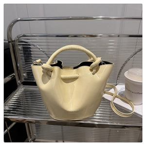Close-up of yellow bucket bag with knotted handle, drawstring closure, and smooth leather