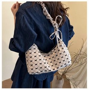 Détail du sac sous le bras crème chic avec motifs nœuds et bandoulière plissée élégante