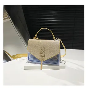Détail du rabat pailleté doré avec pompon métallique sur sac en PVC bleu clair