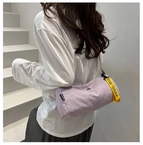 Detail der hellvioletten Nylon-Umhängetasche mit gelbem 'Ordinary unique' Bandakzent