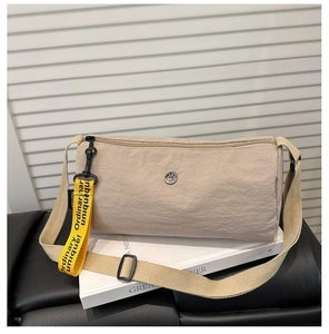 Nahaufnahme der khakifarbenen Nylon-Umhängetasche mit Metall-Logo und gelbem Gurt