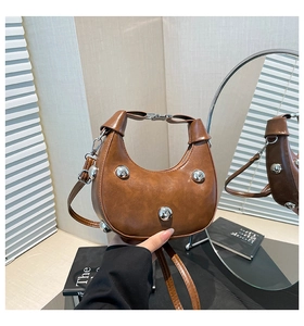 Detail of brown crescent bag with vintage leather texture and large silver metal studs