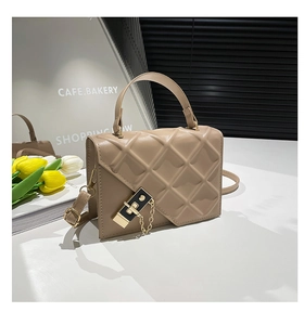 Dettaglio borsa quadrata beige trapuntata con chiusura dorata e patta asimmetrica