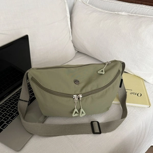 Détail du sac bandoulière en nylon vert sauge avec double fermeture éclair et logo rond