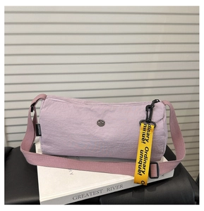 Detail der hellvioletten Zylindertasche aus Nylon mit gelbem Gurt und Metall-Logo-Elementen