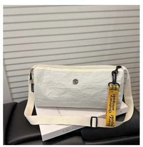Detailansicht einer weißen Nylon-Umhängetasche mit Textur und gelbem Logo-Band