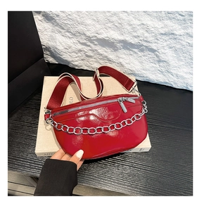 Detail der roten glänzenden Brusttasche mit silberner Kette und gestreiftem Schultergurt
