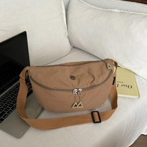 Sac croissant en nylon kaki avec bandoulière réglable et logo sur canapé blanc